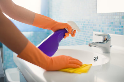 Housecleaner_cleaning_the_sink_wearing_orange_gloves_using_purple_cleanser_and_wiping_down_sink.jpg